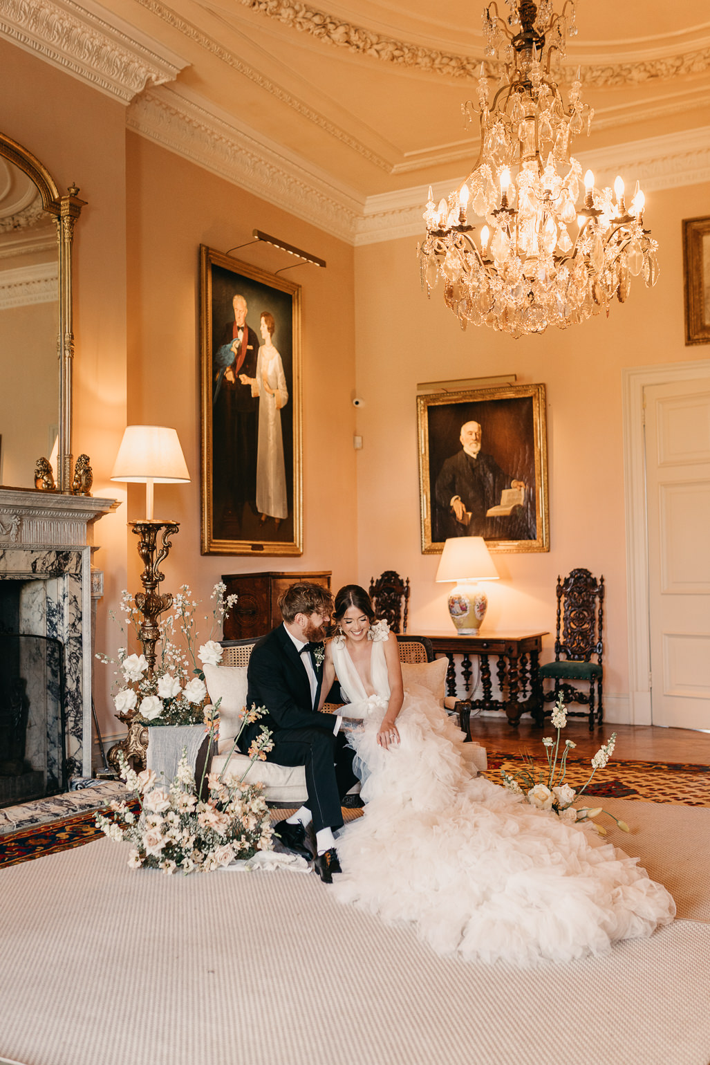 Bride in white ruffled Millia London wedding dress with groom in black tie in the music room of Stansted House