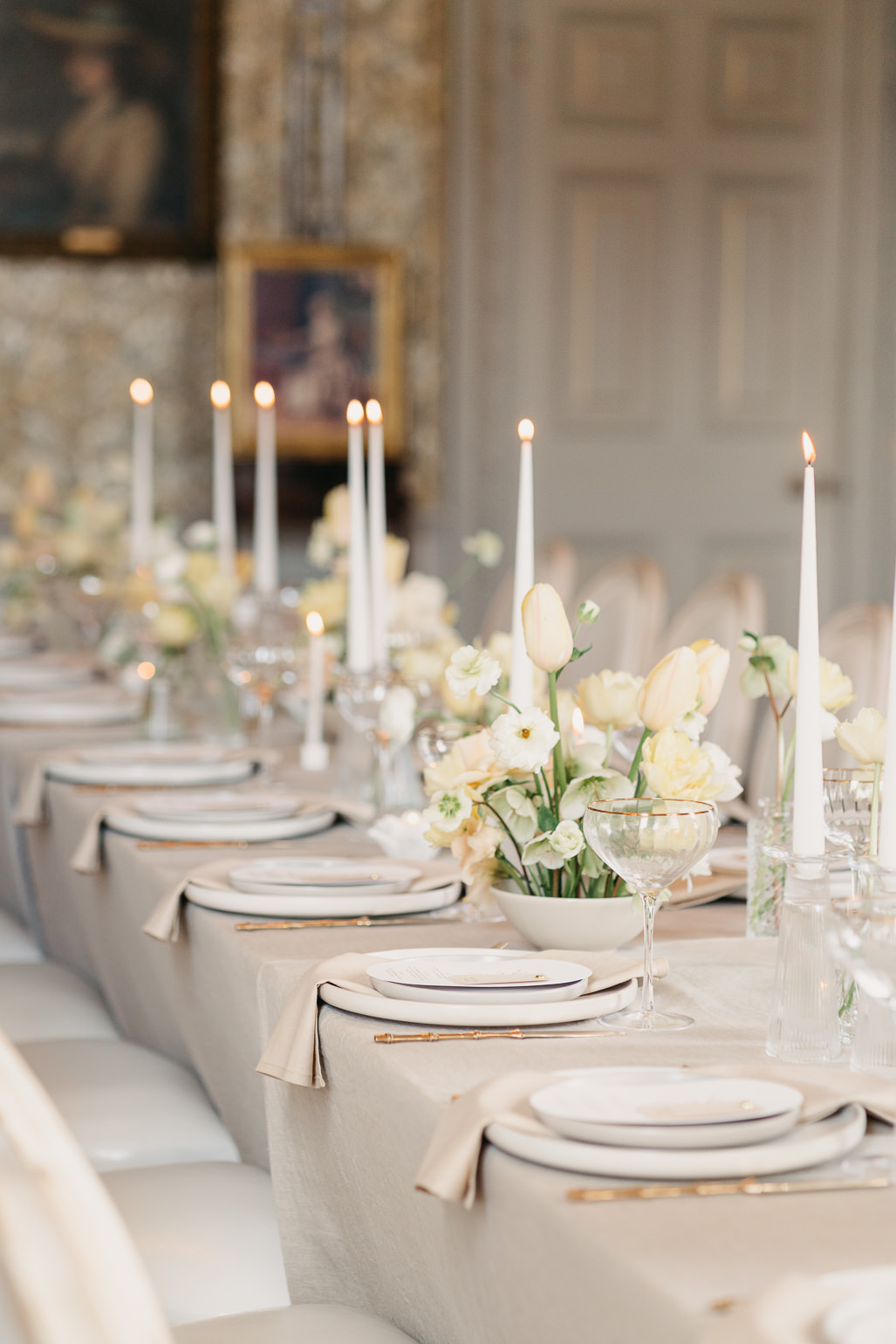 Spring wedding table with yellow tulips and soft pastel colours, gold cutlery and oval wedding menus in the drawing room of Stansted Park